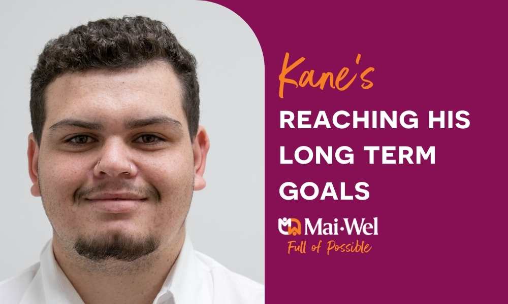 A maroon graphic half-filled with a smiling man's face, with the text 'Kane's reaching his long term goals'